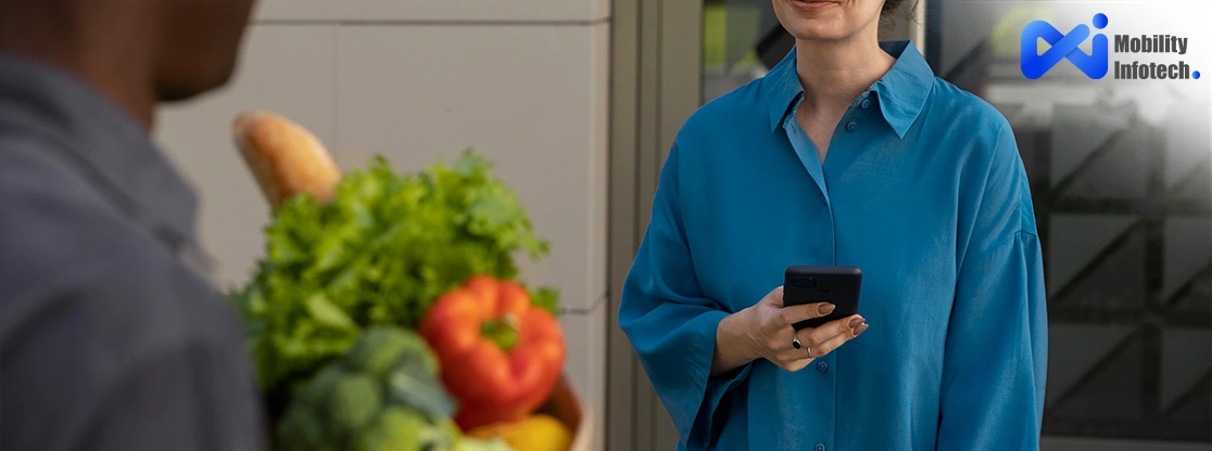 Woman receiving fresh grocery delivery while holding phone.